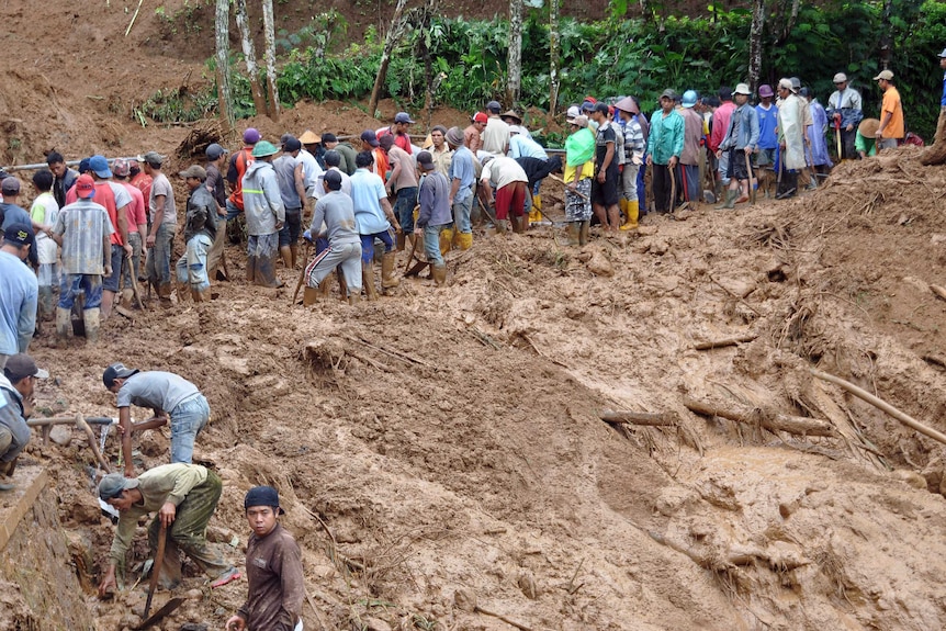 Indonesian villagers dig through mud