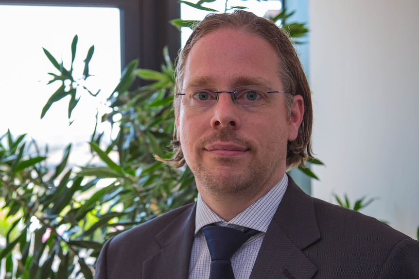 Man in glasses and suit in an office.