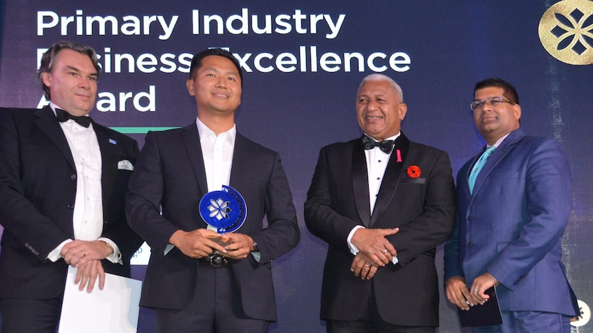 Four men in suits pose for onstage at the  Prime Minister’s International Business Awards. 