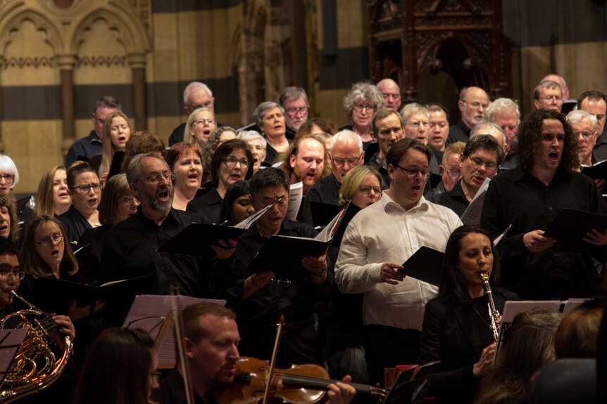 A large choir performs with an orchestra in a cathedral.