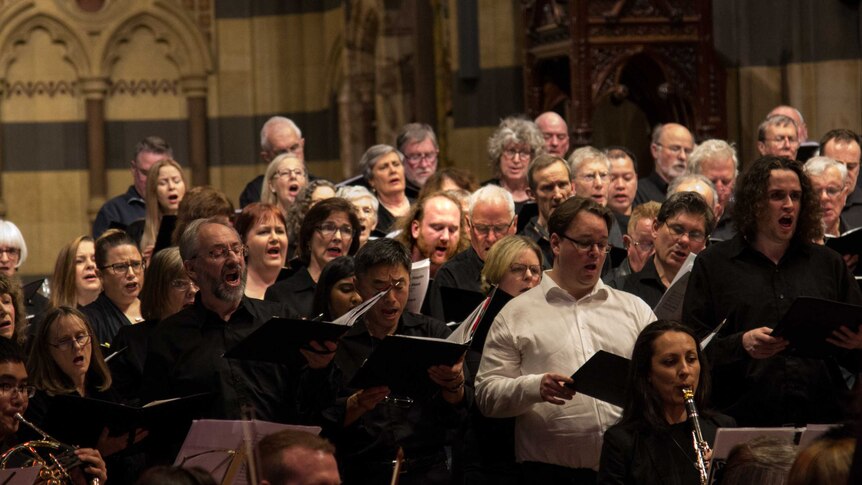 A large choir performs with an orchestra in a cathedral.