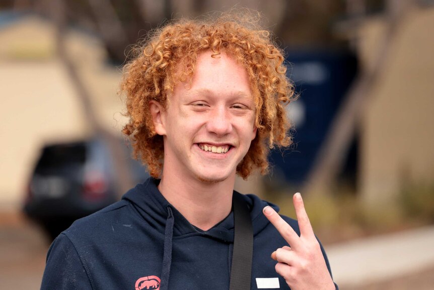 A portrait of a teenager with curly red hair, big smile on his face