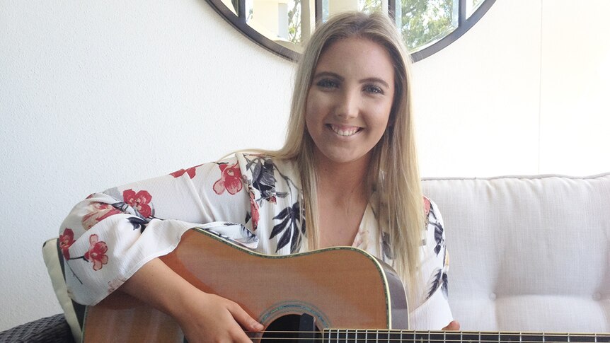 Brisbane singer Sabrina Schultz sits with her guitar in her house in August 2017.