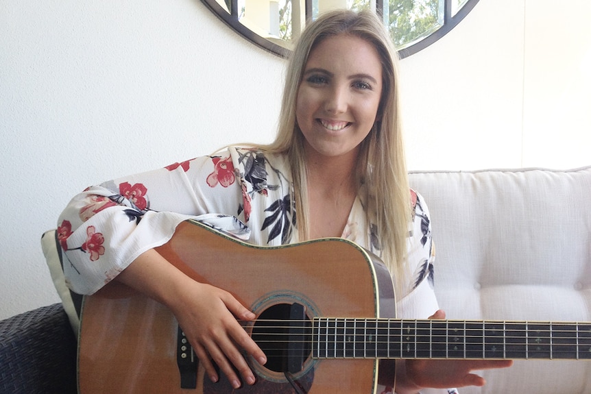 Brisbane singer Sabrina Schultz sits with her guitar in her house in August 2017.