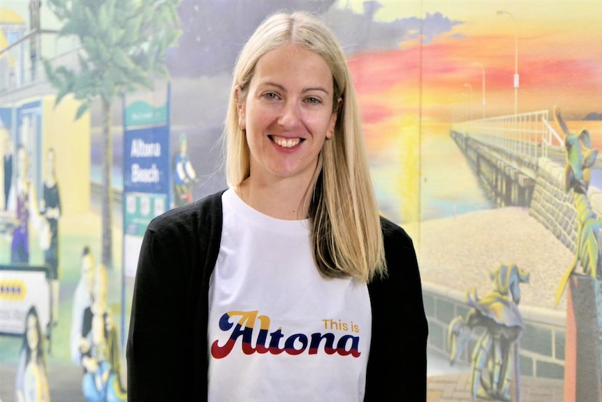 Cr Daria Kellander smiles in front of a mural of Altona beachfront