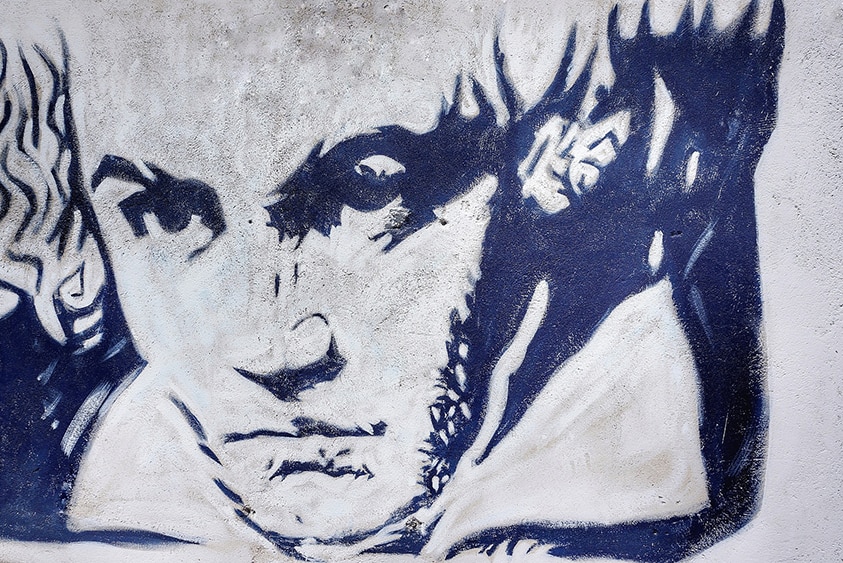 A large black stencil of Beethoven's head on a white wall in Verona, Italy.