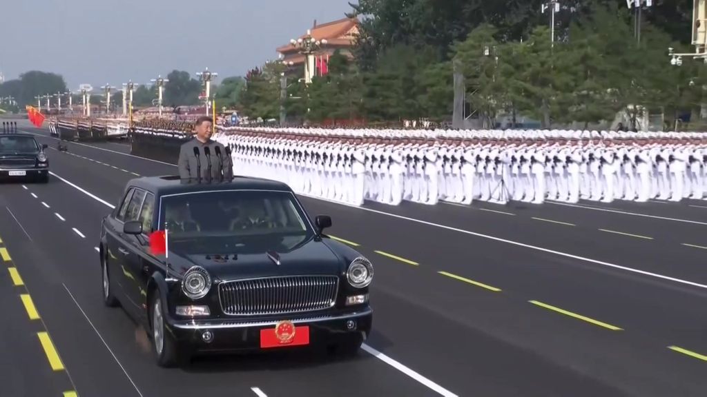 Xi Jinping on a car driving past thousands of soldiers. 