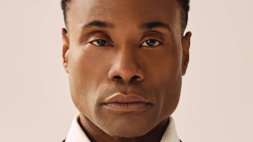 Portrait of a black man staring into the camera. Wearing a black jacket with rhinestone edged lapels.