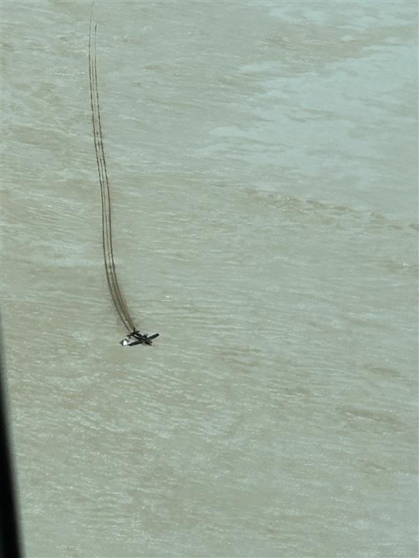 A birds eye view of a light plane resting on sandy ground, with tracks leading up to it
