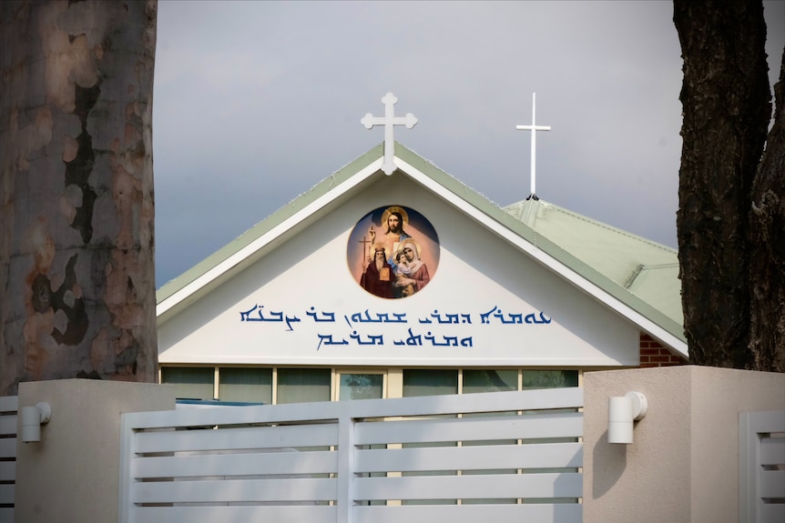 Church sign with cross and painting of religious figures 