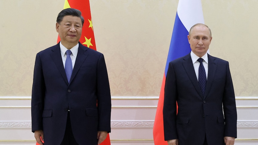 Xi and Putin standing in front of their respective flags at the SCO in Sept 2022
