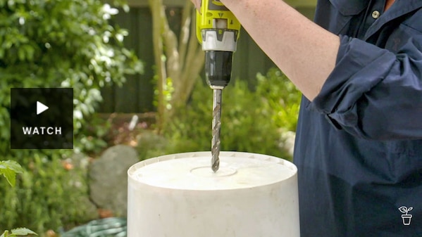 A hole being drilled in the base of an upturned white bucket. Has Video.