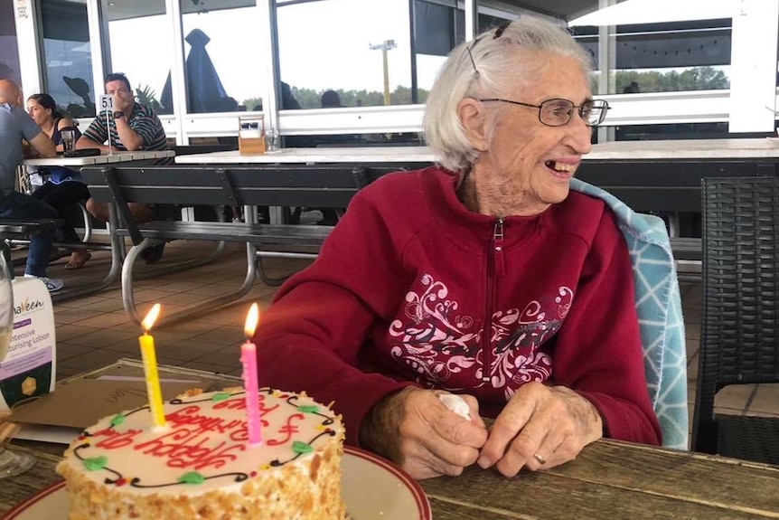 A woman smiling with a birthday cake.