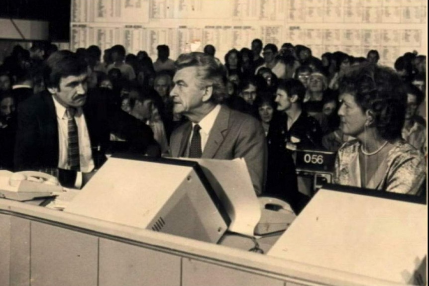 Black and white photo of Barrie Cassidy interviewing Bob Hawke with Hazel Hawke watching in tally room.