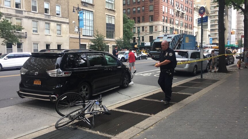 A police officer at the scene after a cyclist was hit and killed by a garbage truck.