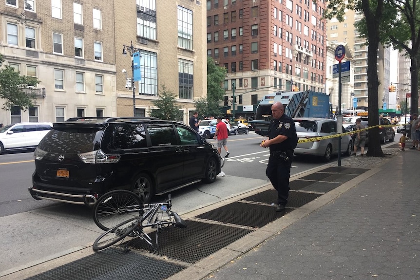 A police officer at the scene after a cyclist was hit and killed by a garbage truck.