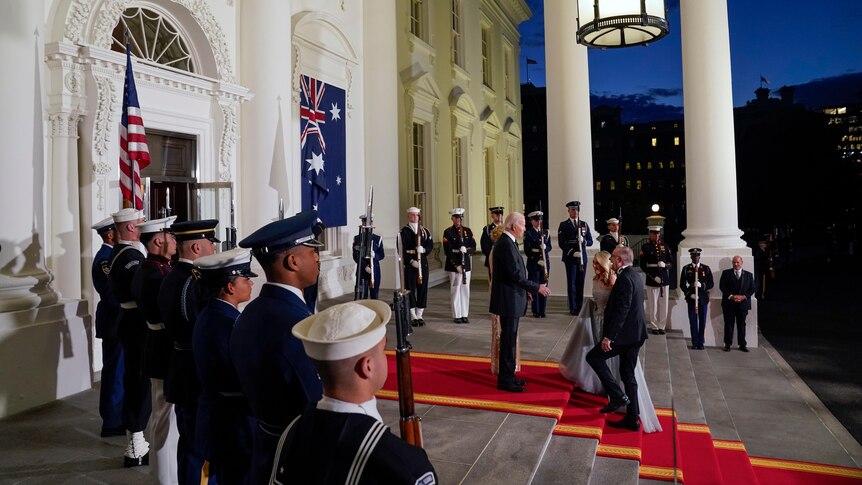 Anthony Albanese and Jodie Haydon walk along a red carpet up the stairs to the White House. The Bidens greet them.