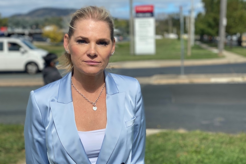 A woman in a blue suit stands outside Canberra Hospital.