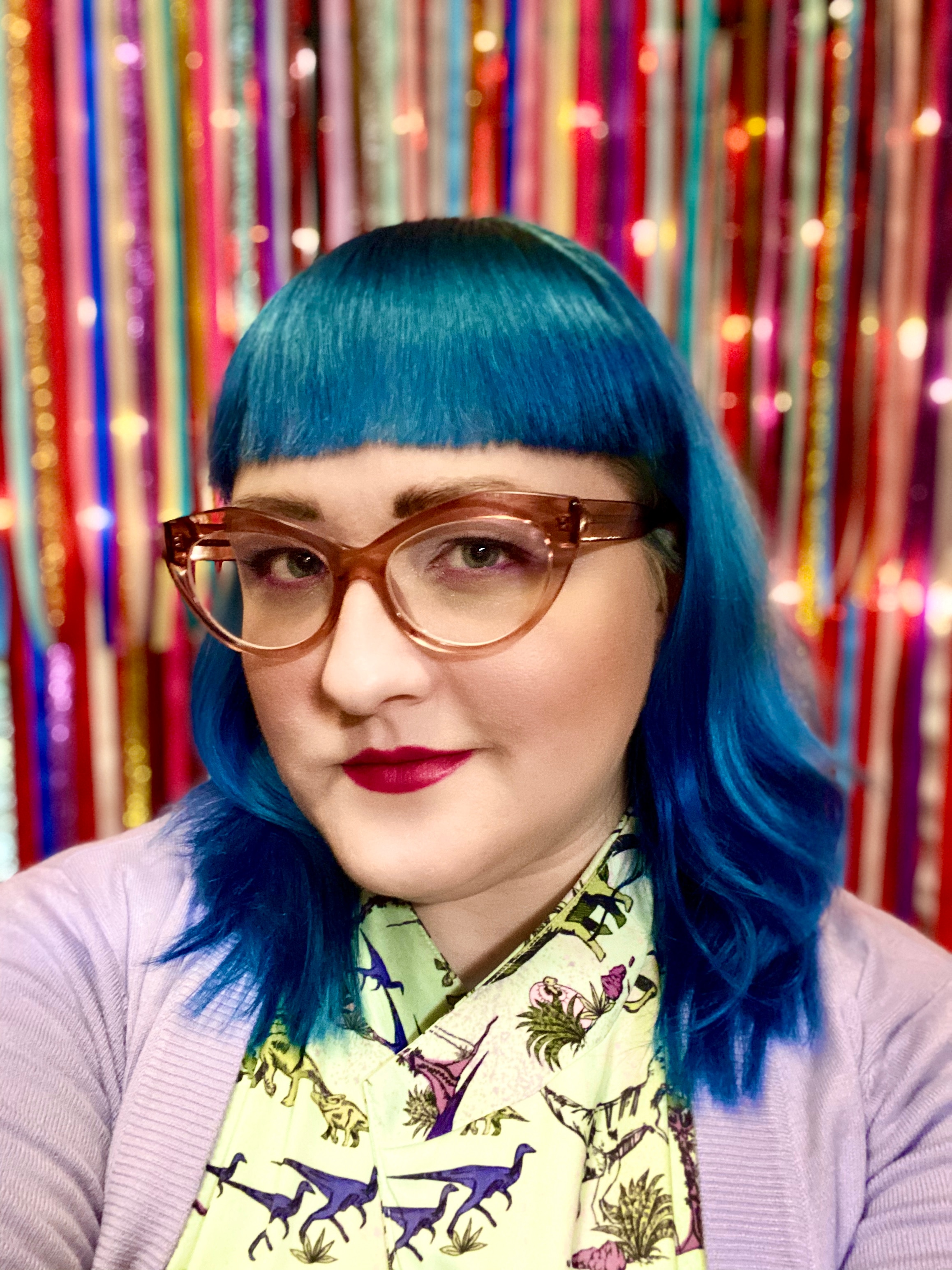 A woman with blue hair and glasses.