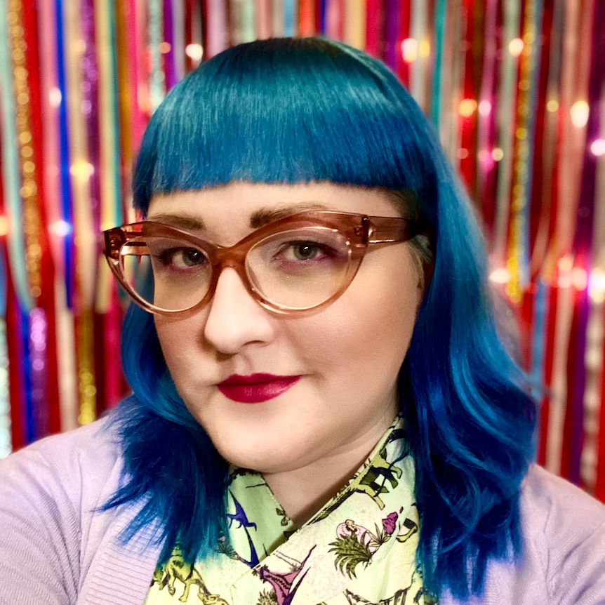 A woman with blue hair and glasses.