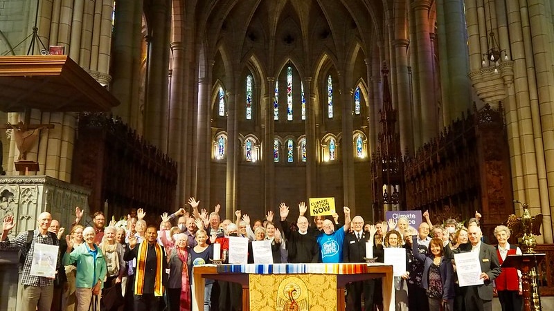 Dozens of people holding banners, some with hands in the air, are pictured inside a church.