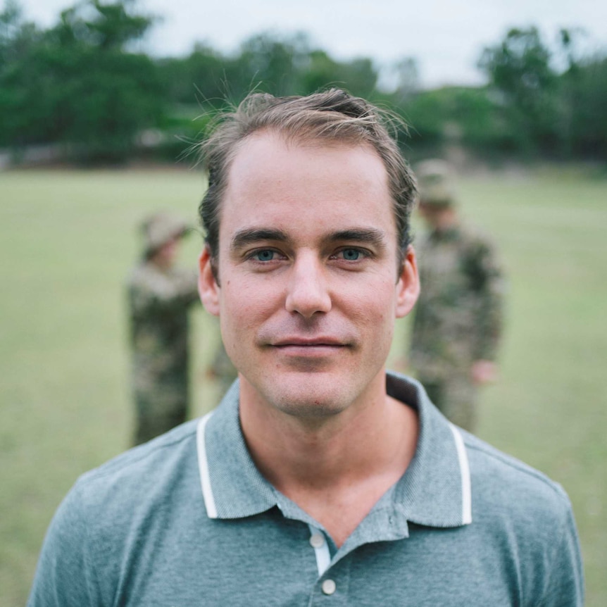 A man wearing a grey top stares at the camera.