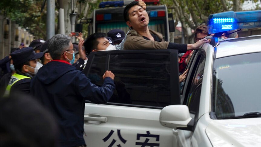 a protester reacts as he is arrested by policemen during a protest on a street in Shanghai, China.