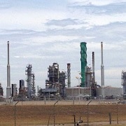 An oil refinery in the background and a security fence in the foreground