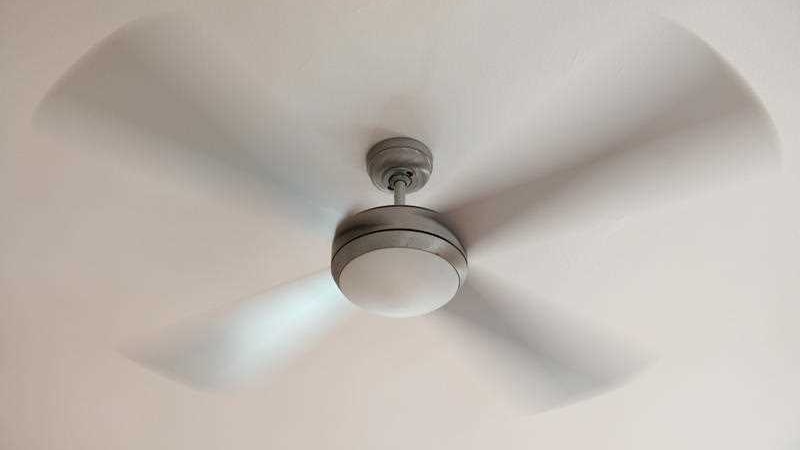 A ceiling fan spins around against a white ceiling.