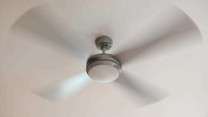 A ceiling fan spins around against a white ceiling.