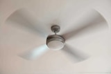 A ceiling fan spins around against a white ceiling.