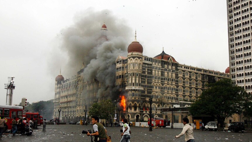 People run in front of a blazing building.