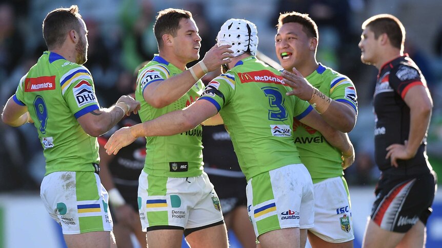 Raiders players celebrate a try against the Warriors