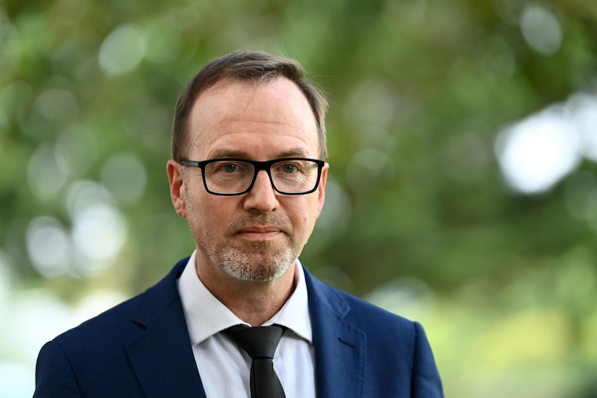 a man wearing glasses talking outdoors