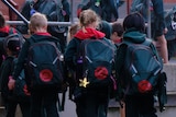 A group of early years primary school students walk into class with their backpacks on.