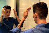 Vivien Houston stands in front of a mirror doing her hair