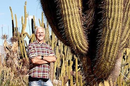 Un bărbat stă lângă un cactus imens
