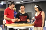 three people around a string instrument