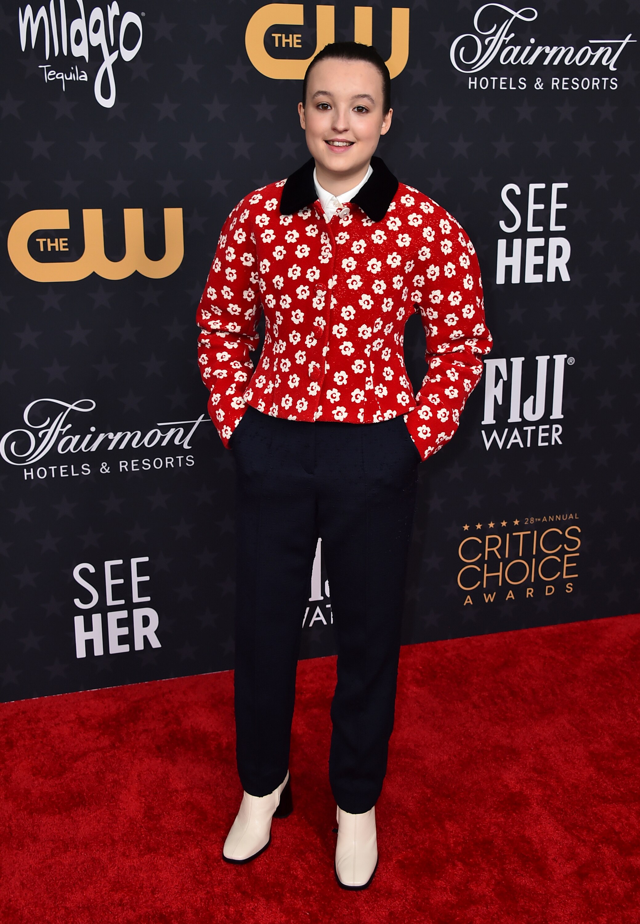 One of the younger nominees, Bella Ramsey goes low key with a red floral pullover.