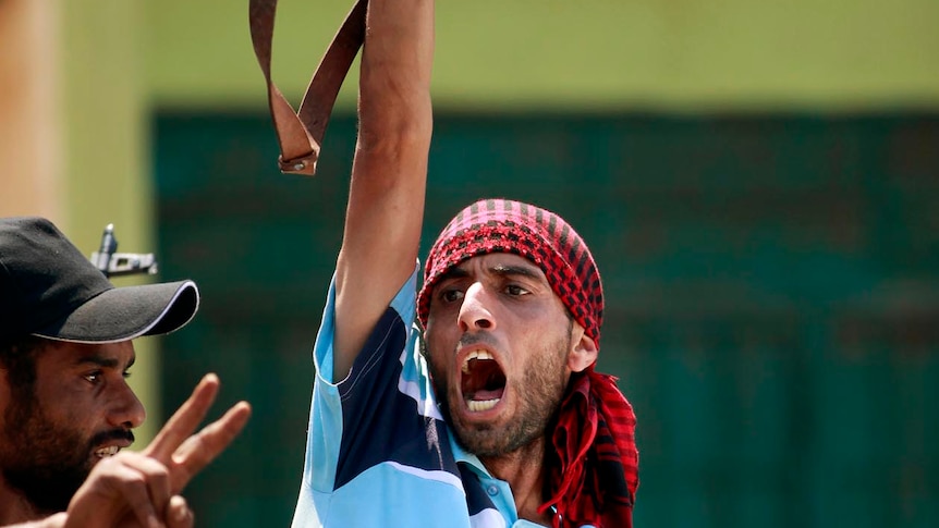 A Libyan rebel fighter raises his weapon and shouts