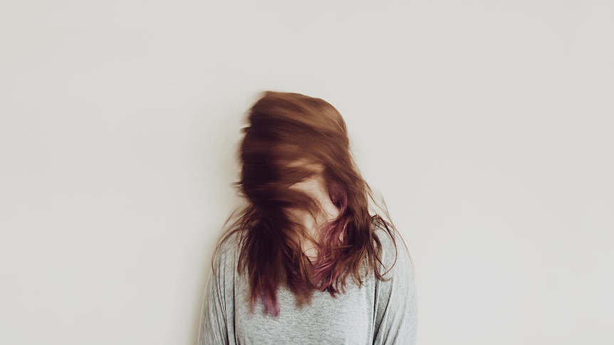 A woman's face is obscured by her red hair