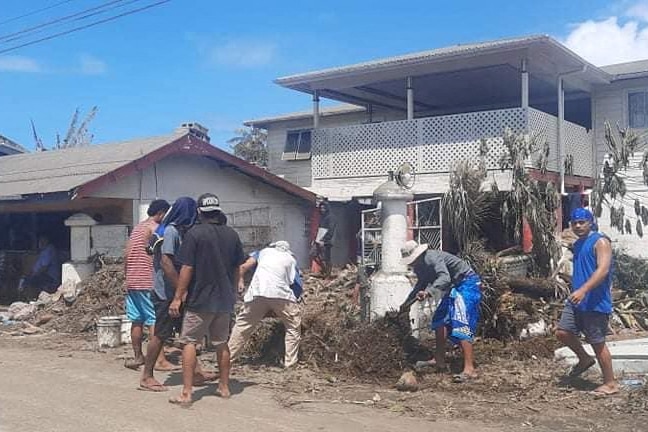 People clean up debris outside homes