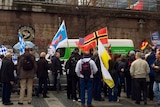 Far right Alternative for Germany supporters hold flags, turn backs at rally.