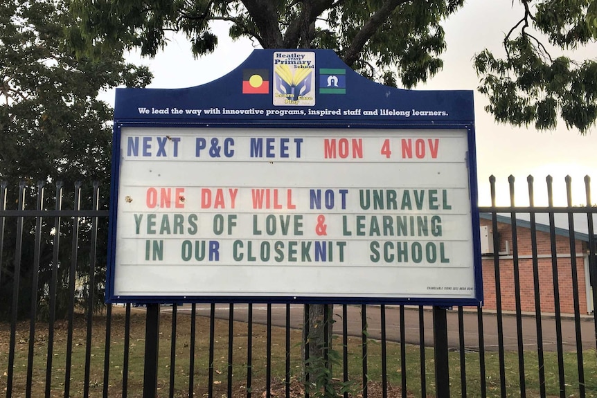 The school sign reads "One day will not unravel years of love and learning in our close knit school"