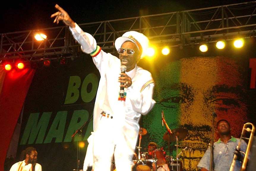 Bunny Wailer performs onstage in a white suit