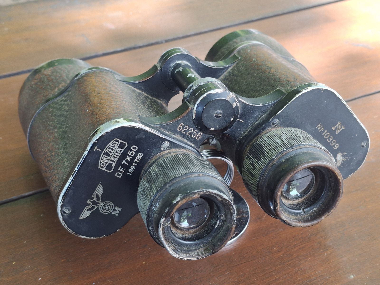 A pair of rusty binoculars with a swastika stamp.