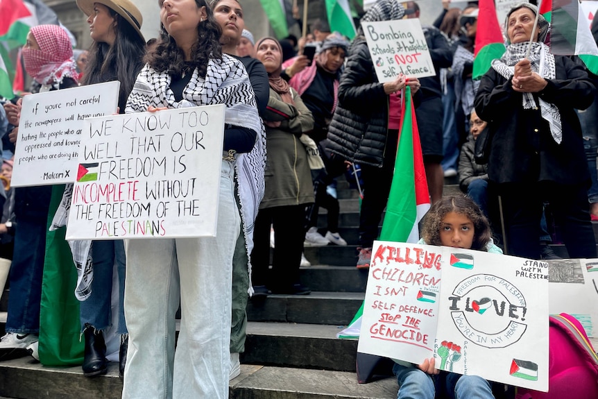 Protesters hold pro-Palestinian signs.
