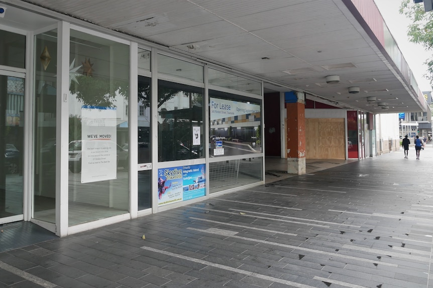 empty shopfronts, glass windows, two people walking past