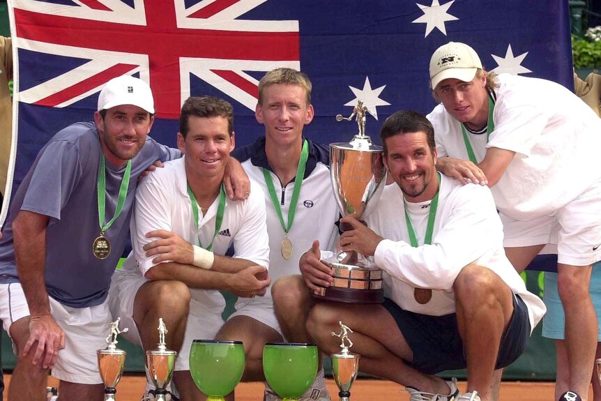 A group of men pose with a tennis trophy.