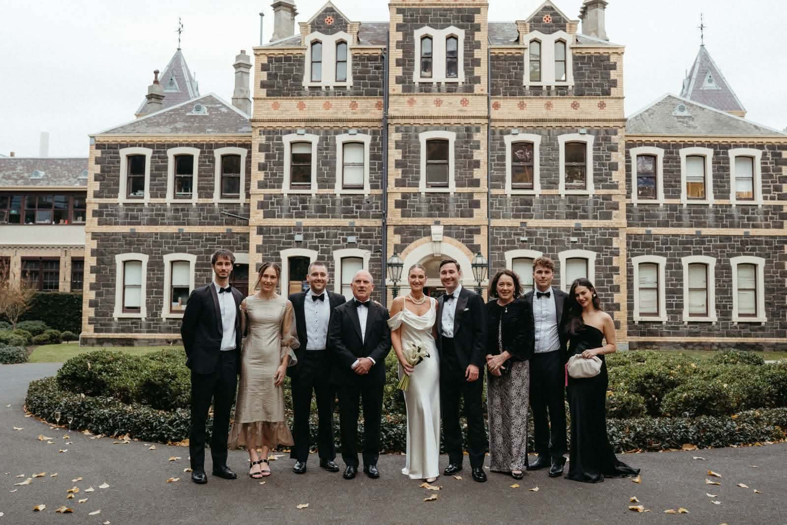 Michael Hurst (second from the right) wearing a black and white suit standing with several other people.